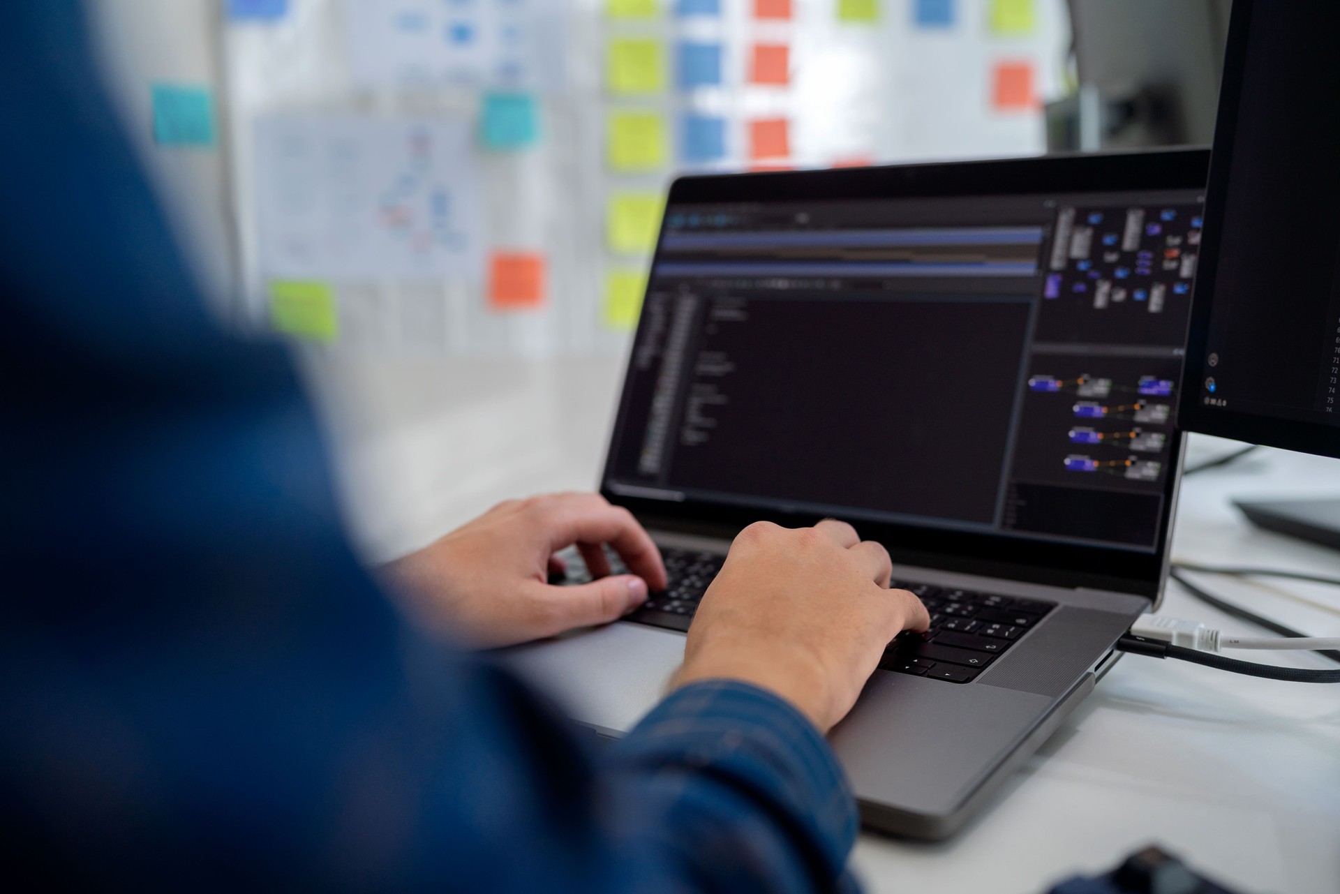 Close-up shot of a programmer's hands typing on a keyboard, creating code for a software project in a modern office environment. Surrounded by advanced technology, the individual is focused on coding for cloud computing, artificial intelligence, and data